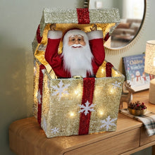 Cargar imagen en el visor de la galería, Papá Noel Saliendo de Caja Decorativo con Luz, Movimiento y Múltiples Melodías Navideñas - 26x26x32 cm, Diseños en Oro (Lazo Rojo) y Rojo (Lazo Verde o Dorado al Azar), Interruptor de Botón y Pilas AA No Incluidas
